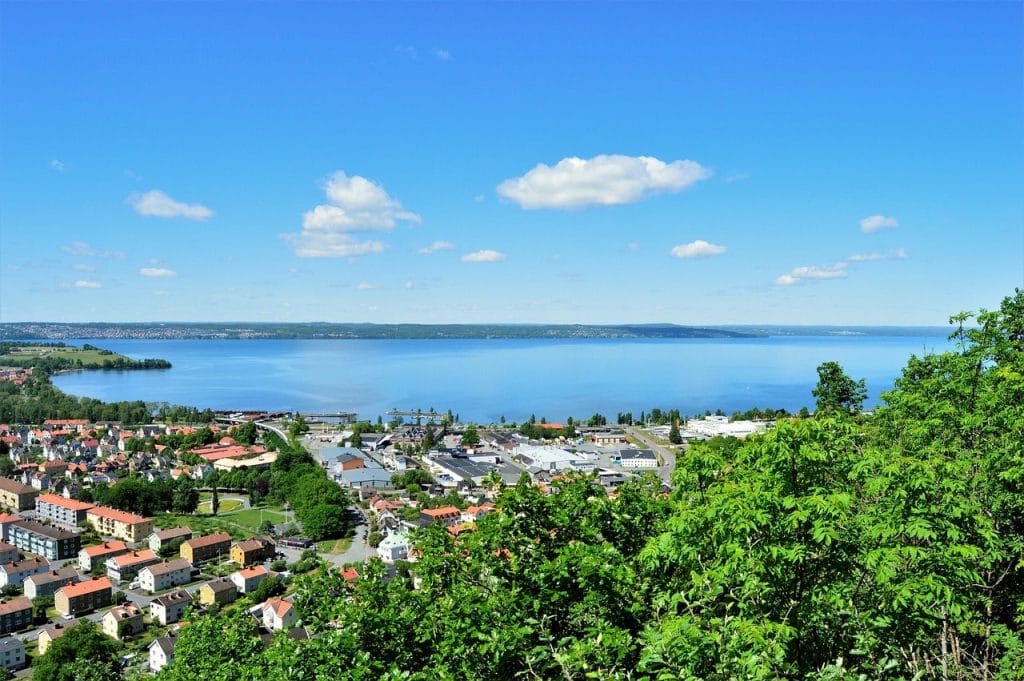 Vista soleada de la orilla del lago Vättern en Suecia, con casas y vegetación. donde darse baños de contraste