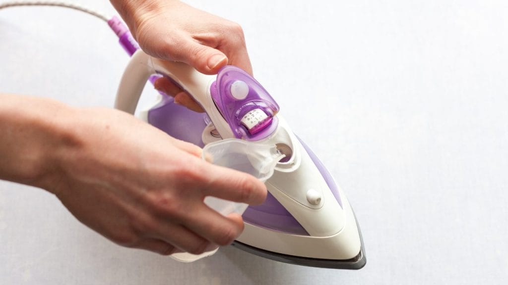 Uso de agua destilada en una plancha de vapor: rellenar la plancha con agua destilada previene la formación de depósitos minerales, asegurando un funcionamiento eficiente y evitando manchas en la ropa.