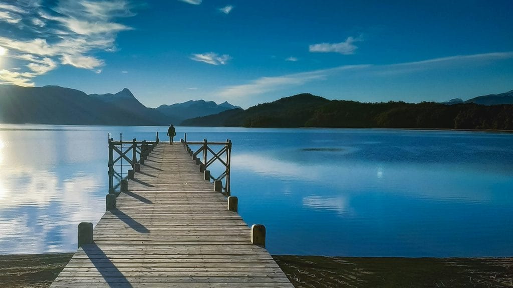 hombre frente al lago en día soleado en Bariloche