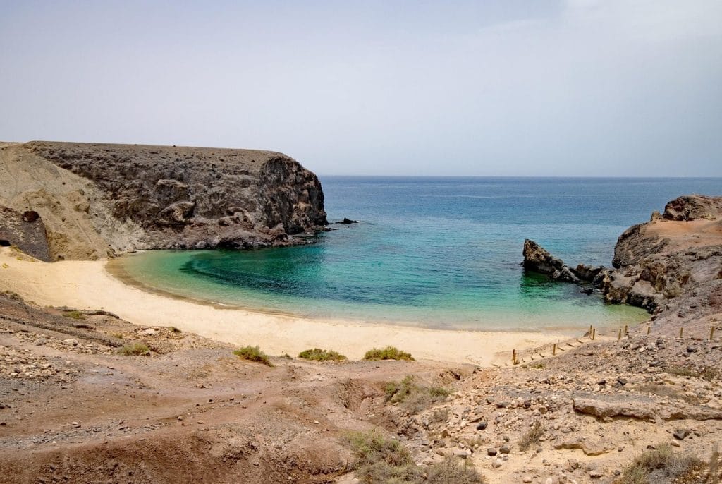 Playa de arena dorada aguas azules y acantilados