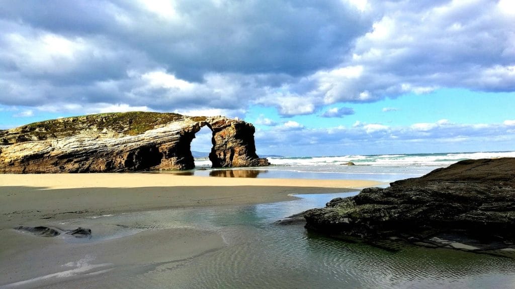 playa con arco de piedra y arena dorada